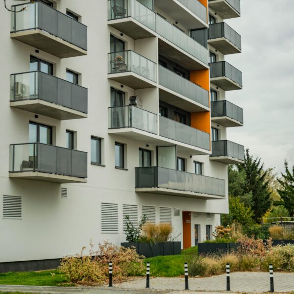Contemporary apartment complex featuring glass balconies and landscaped surroundings.